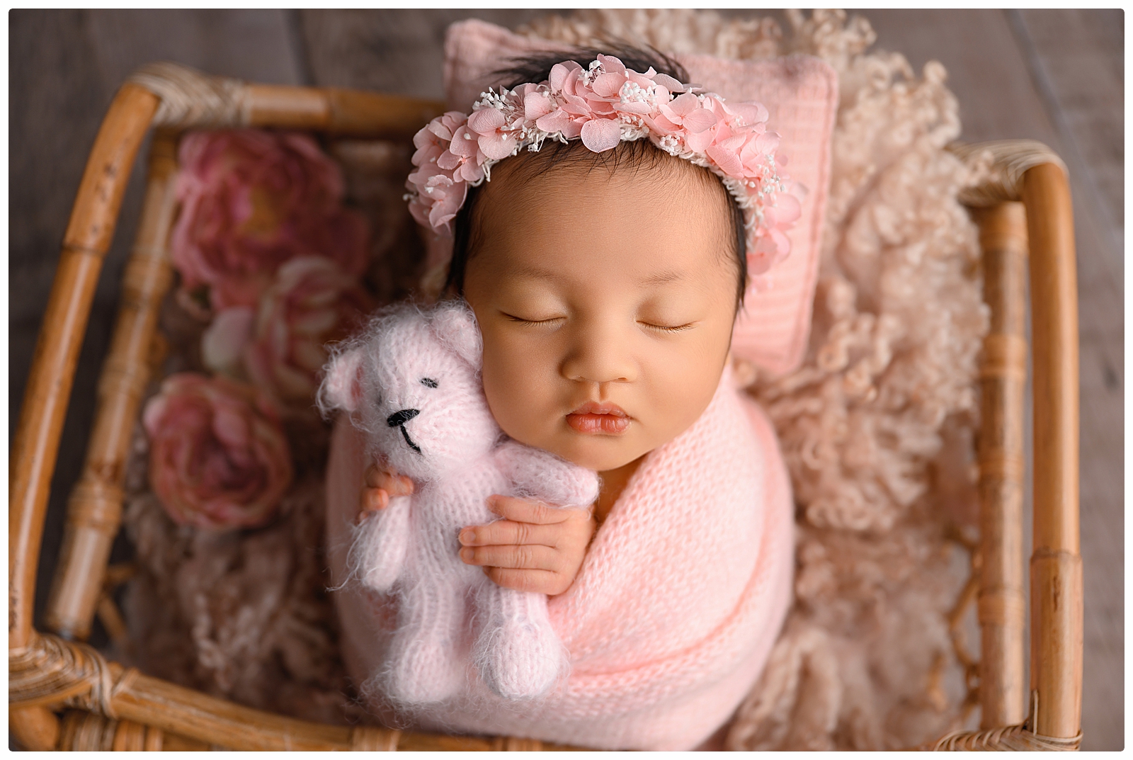 Newborn baby wrapped in a soft blanket being posed by a photographer in West Palm Beach, FL.